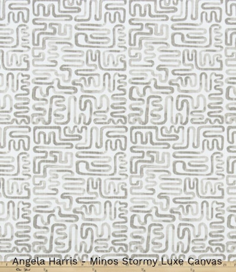 May include: White fabric with a repeating pattern of gray, abstract shapes. The text "Angela Harris - Minos Stormy Luxe Canvas" is printed at the bottom of the image.
