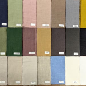 Può includere: Una collezione di 30 campioni di tessuto in vari colori, tra cui blu, verde, rosso, marrone, grigio e beige. I campioni sono disposti in righe e colonne, e ogni campione è etichettato con il nome del suo colore.