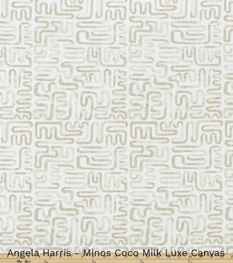 May include: Cream-colored fabric with a repeating pattern of abstract, maze-like shapes in a light tan color. The text "Angela Harris - Minos Coco Milk Luxe Canvas" is printed at the bottom of the image.