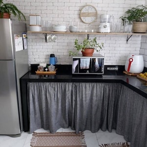 May include: A kitchen counter with a black countertop and a white brick backsplash. The counter has a microwave, an air fryer, and a coffee maker. The counter is decorated with a black and white checkered tablecloth and a brown rug.