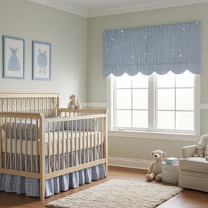 Puede incluir: Un cuarto de bebé con una cuna de madera clara, ropa de cama a cuadros azules y blancos y una cenefa a juego. Dos ilustraciones enmarcadas en azul y blanco cuelgan de la pared. Una alfombra beige y animales de peluche completan la decoración.