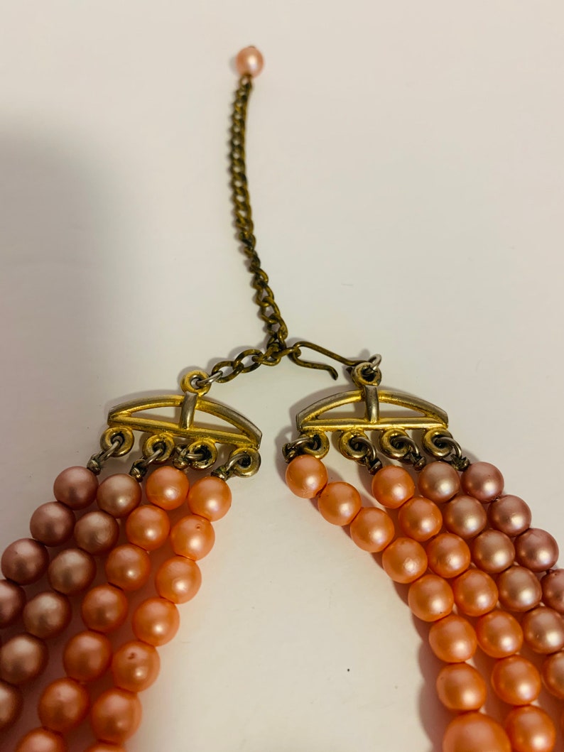 Multi strand pink and peach beaded necklace with hook closure.