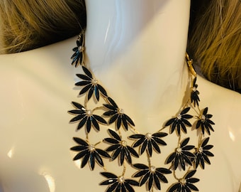 Black facetted beads with three rows of half flowers with clear rhinestone centre with gold tone trim and chain.