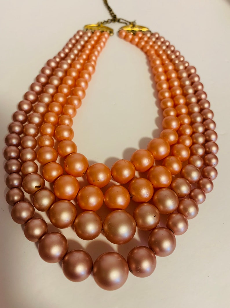 Multi strand pink and peach beaded necklace with hook closure.