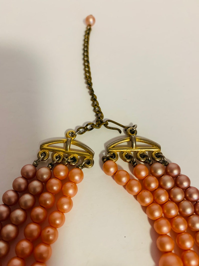 Multi strand pink and peach beaded necklace with hook closure.