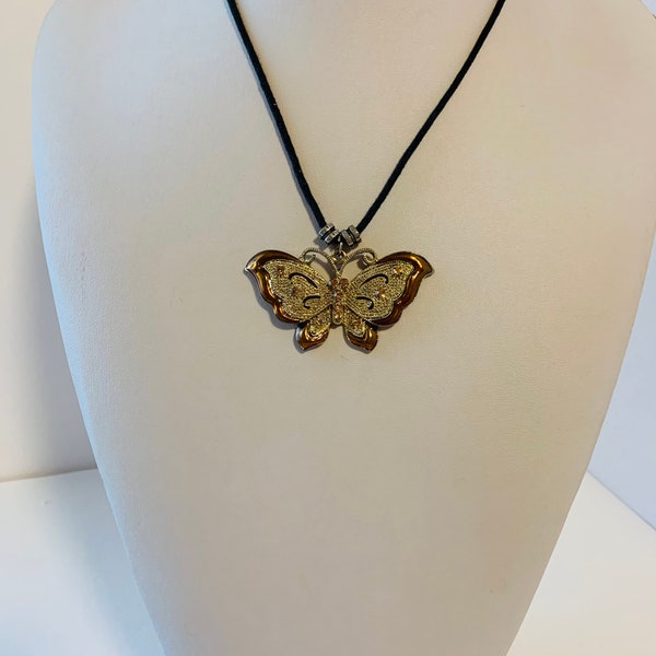 Collier pendentif papillon couleur bronze avec strass taupe et métal doré sur un cordon noir.