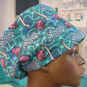 May include: A blue and green surgical scrub hat with a pattern of brains and the words "Neuro Surgery" repeated.