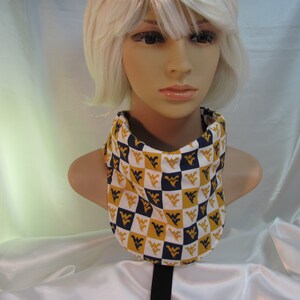 May include: A white neck gaiter with a checkered pattern of gold and navy blue. The pattern features a repeated logo of a stylized 'W' with a 'V' inside.