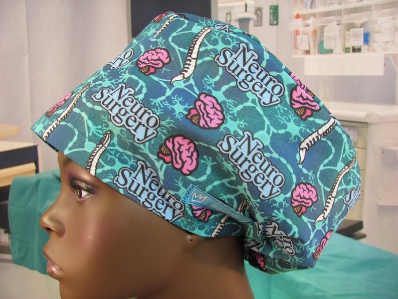 May include: A blue and green surgical scrub hat with a repeated pattern of pink brains, a spinal cord, and the text "Neuro Surgery".