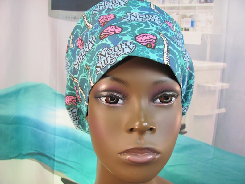May include: A turquoise blue surgical scrub hat with a white and pink brain pattern. The hat has the text "Neuro Surgery" repeated on it.