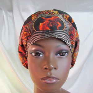 May include: A black, orange, and gray patterned surgical cap with a stylized image of a dragon in the center.