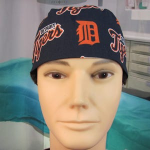 May include: A blue and orange baseball cap with the Detroit Tigers logo and the words "Detroit Tigers" printed on it.