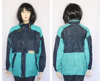 May include: A blue and teal color block jacket with a zipper and snap closure. The jacket has a small logo patch on the left chest.