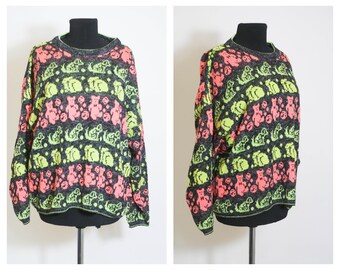 May include: A black sweater with a colorful pattern of pink and green bears. The sweater has a crew neck and long sleeves.