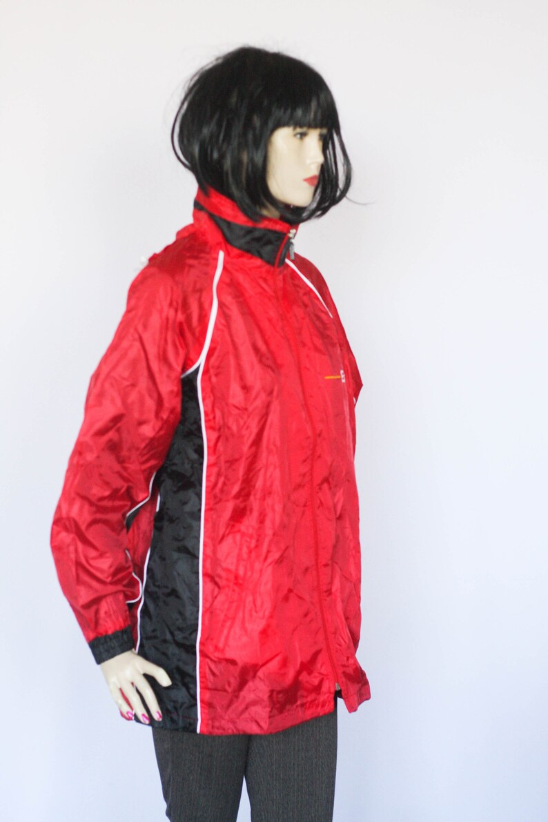 May include: A red and black windbreaker jacket with white piping. The jacket has a zipper closure and a stand-up collar.
