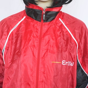 May include: Red windbreaker jacket with black and white trim and a yellow logo that says "Enbu".