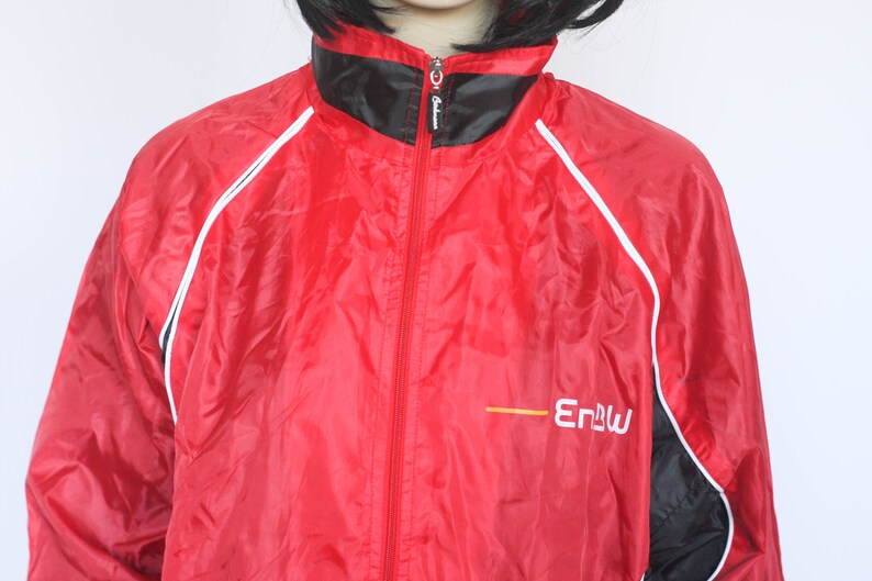 May include: Red windbreaker jacket with black and white trim and a yellow logo that says "Enbu".