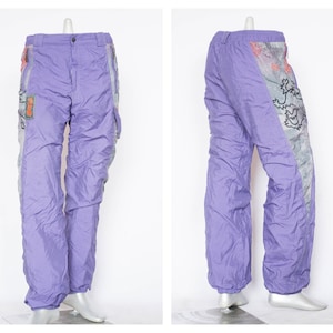 May include: Purple nylon pants with a graphic print on one leg. The print features a lion and other abstract designs in black, white, and orange.