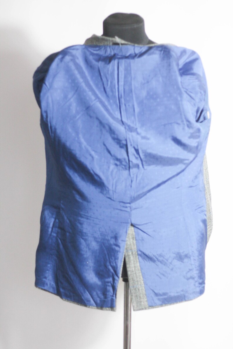 Pu&ograve; includere: Un blazer a spina di pesce grigio e nero con fodera blu. Il blazer &egrave; sbottonato e girato al rovescio, mostrando la fodera.