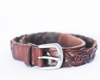 May include: A brown leather belt with a braided design and a silver buckle.