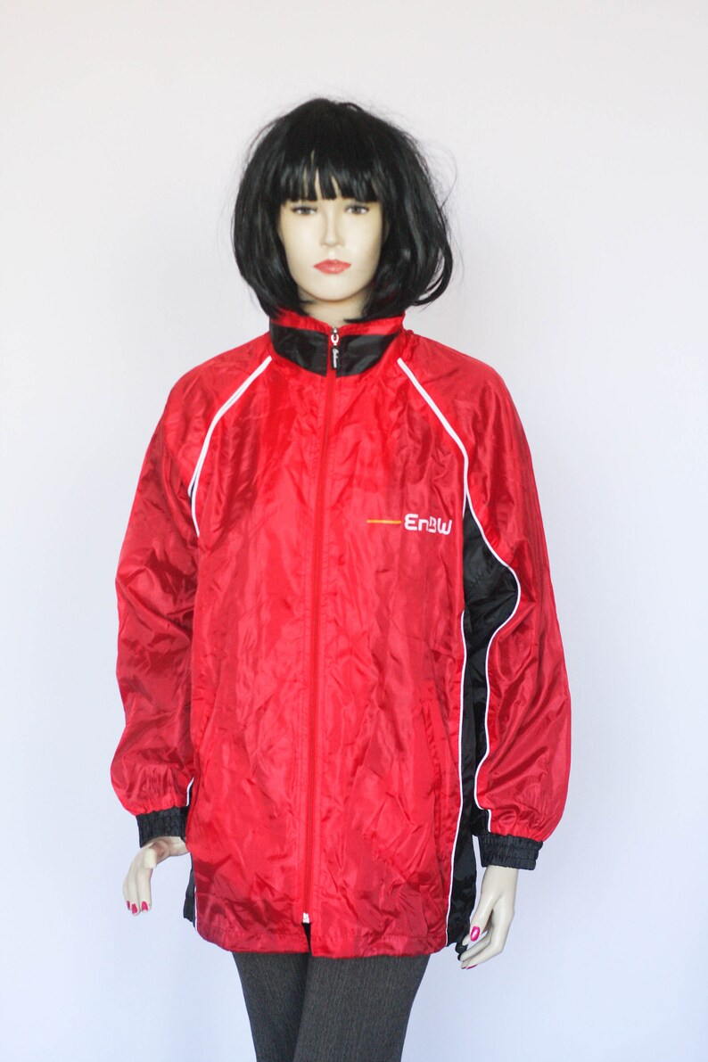 May include: Red, black, and white windbreaker jacket with white piping and a black zipper. The jacket has the word "Erbu" printed on the front in white.