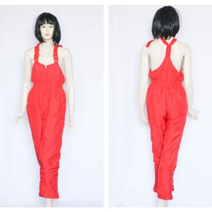 May include: Red ski jumpsuit with adjustable straps and a cinched waist.