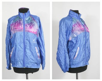 May include: A blue windbreaker jacket with a multi-colored abstract print on the front and back. The jacket has a zipper closure and two pockets.