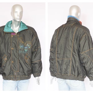 May include: A dark green puffer jacket with a zipper closure and gold buttons. The jacket has a contrasting teal and purple lining and features embroidered graphics on the front.