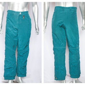 Puede incluir: Pantalón de esquí de color turquesa con abertura de pierna con cremallera y cierre de botón en la cintura.