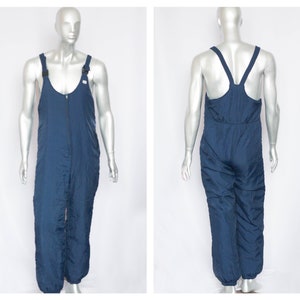 Może przedstawiać: Niebieski kombinezon narciarski z regulowanymi szelkami i zamkiem błyskawicznym.