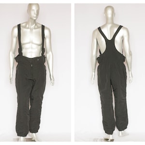 May include: Black ski overalls with suspenders. The overalls have a zipper closure and two pockets on the front.