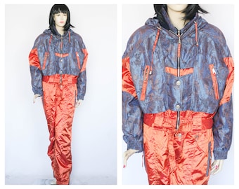 May include: A blue and orange ski suit with a patterned jacket and a zipper closure. The suit has a hood and multiple pockets.