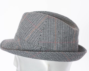 May include: A gray fedora hat with a plaid pattern featuring red and orange accents. The hat has a short brim and a structured crown. This classic hat is a stylish accessory.