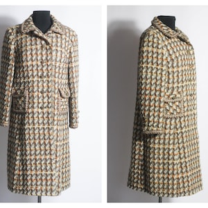 May include: A long, brown, white, and orange tweed coat with a button closure and pockets. The coat is on a mannequin.