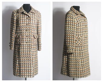 May include: A long, brown, white, and orange tweed coat with a button closure and pockets. The coat is on a mannequin.
