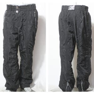 Könnte beinhalten: Schwarze Skihose mit Reißverschlussdetail an den Beinen und einem Kordelzugbund.