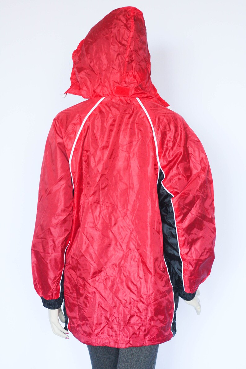 May include: Red and black hooded jacket with white piping. The jacket has a zipper closure and a drawstring hood.