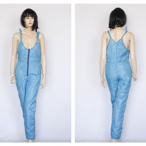 May include: A light blue quilted jumpsuit with a zipper down the front and thin shoulder straps.