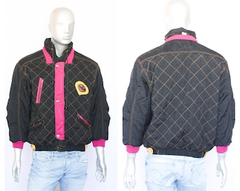 Op de afbeelding: Een zwart gewatteerd jack met roze en gele accenten. Het jack heeft een ritssluiting en een opstaande kraag. Het jack is gevoerd met een zwarte stof.
