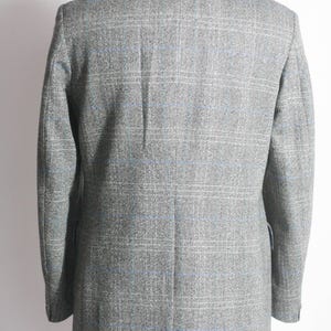 Pu&ograve; includere: Un blazer grigio con un motivo a quadri blu e bianco.