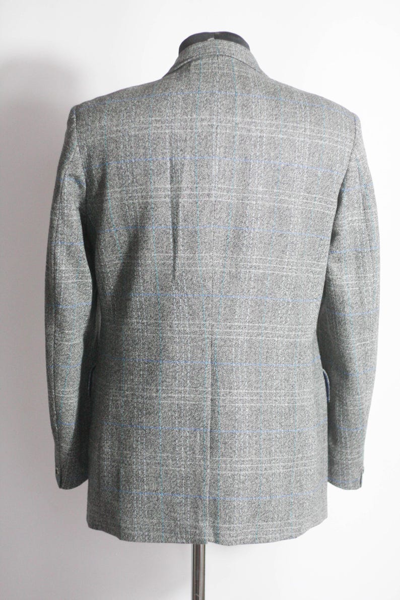 Pu&ograve; includere: Un blazer grigio con un motivo a quadri blu e bianco.