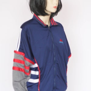 Peut inclure: Une veste zipp&eacute;e bleu marine avec des rayures rouges, blanches et grises sur les manches. La veste a un petit logo Adidas sur la poitrine.
