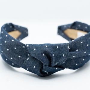 May include: A navy blue headband with white polka dots, knotted in the center.