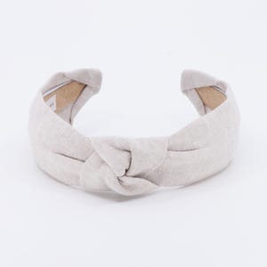 May include: A light gray knotted headband made of fabric.
