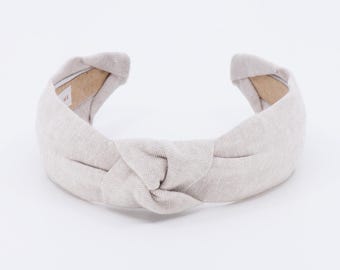May include: A light gray knotted headband made of fabric.