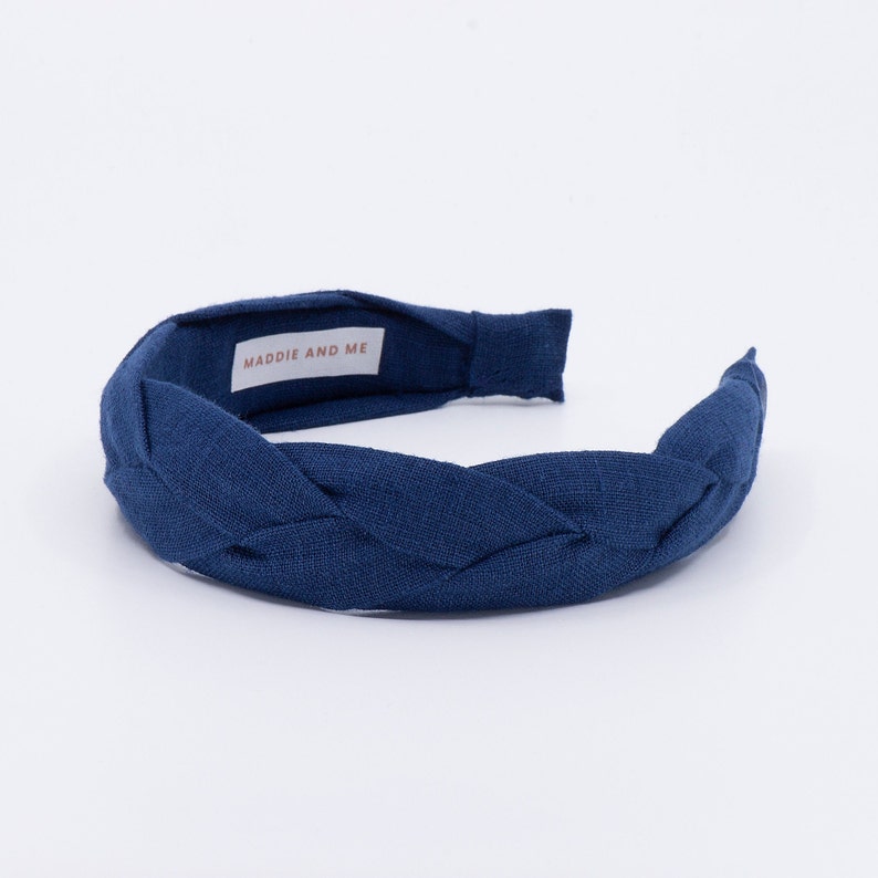 May include: A navy blue braided headband with the text "MADDIE AND ME" on the inside.