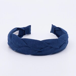 May include: A dark navy blue braided headband made of linen fabric.