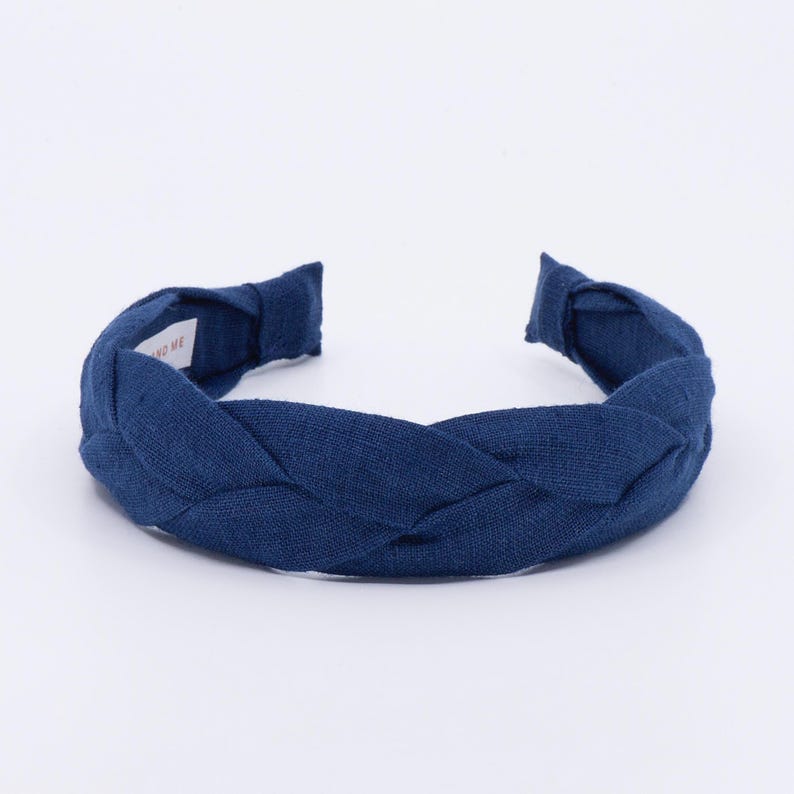 May include: A dark navy blue braided headband made of linen fabric.
