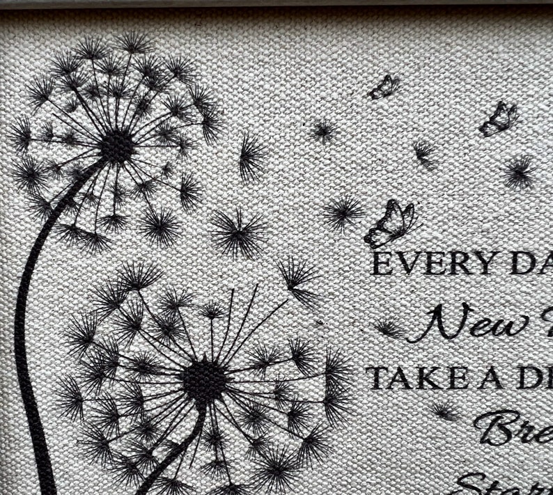 May include: Black and white illustration of two dandelion seeds with butterflies flying away. The text "EVERY DAY IS A NEW DAY, TAKE A DEEP BREATH, START AGAIN" is printed below the dandelions.