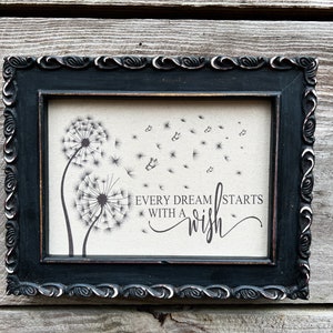 May include: Black framed canvas print with a dandelion design and the text "Every dream starts with a wish".